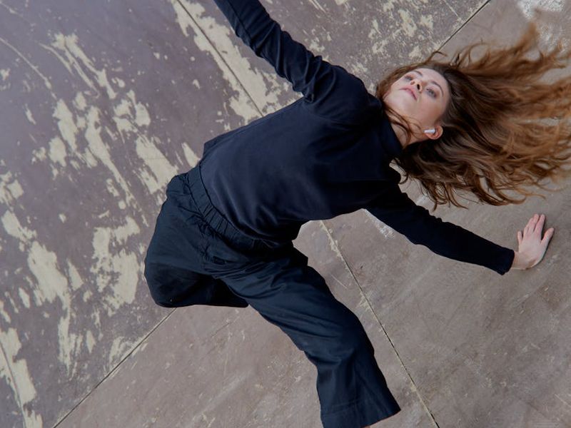 Person performing a fluid stretching movement in a minimalist room.